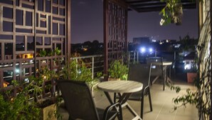 An outdoor patio with a round table and chairs, surrounded by a wooden lattice structure. - Sapphire Court (Accra)