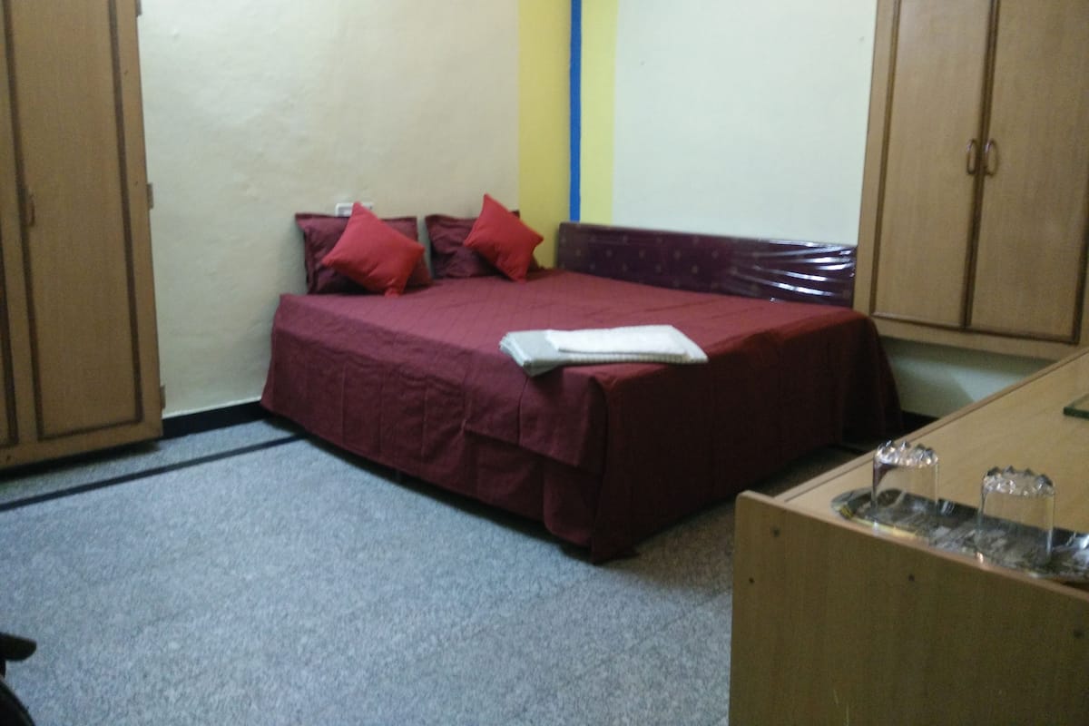 Ein Schlafzimmer mit Bett, Kissen, Nachttisch und Kleiderschrank.