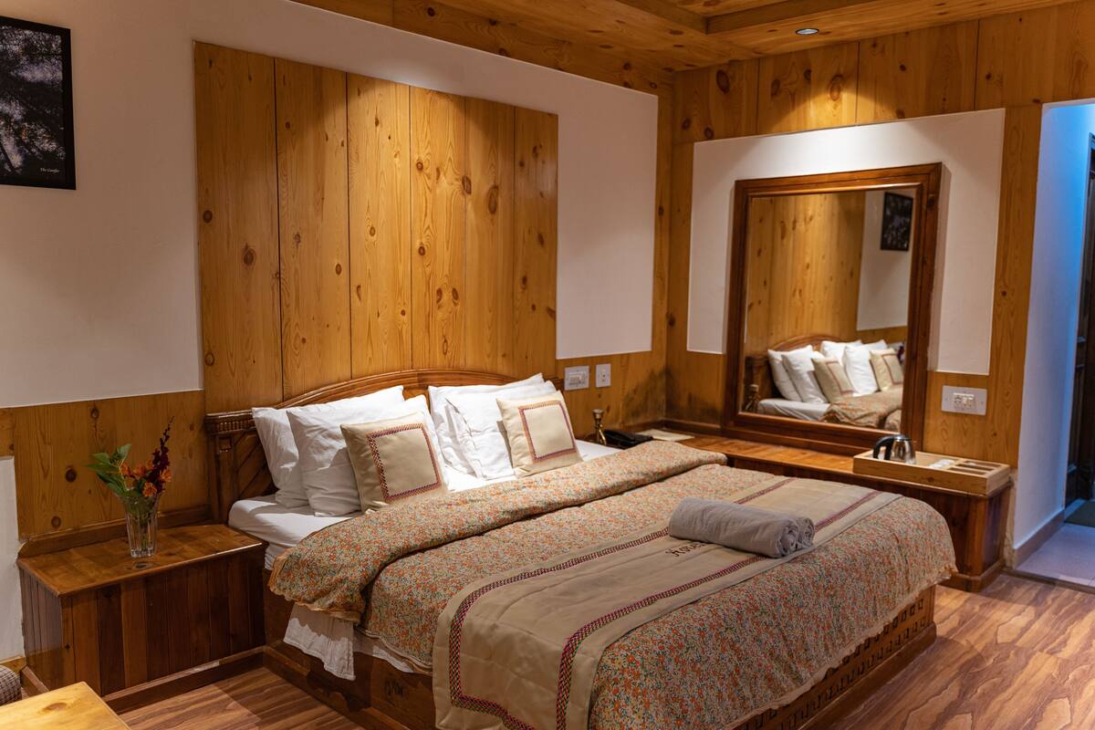 Un dormitorio con paneles de madera, una cama grande, mesitas de noche y un espejo.