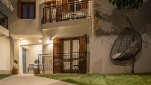 Un bâtiment à deux étages doté d’un balcon, d’un espace extérieur aménagé pour s’asseoir et d’un fauteuil suspendu.