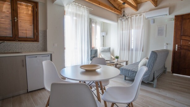 Un espace de vie compact comprenant une cuisine, un coin repas et un petit salon avec un canapé et des fauteuils.