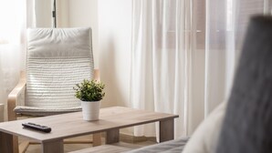 Un salon moderne avec un fauteuil confortable, une petite table sur laquelle est posée une plante en pot et une télécommande sur la table.