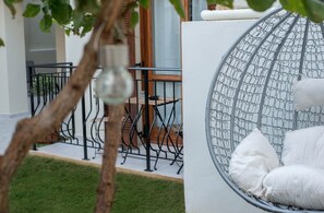 Un jardín con una silla de metal y un colgador de luz.