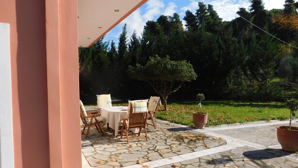 An outdoor patio with stone flooring, a round table, and four chairs. - Villa Aris (Archaia Olympia)