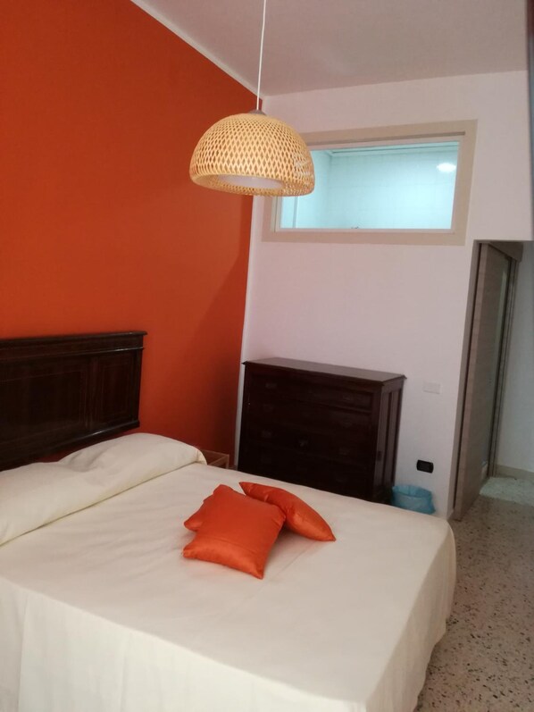 A bedroom with a bed, a dresser, a window, and a hanging light fixture. - Spira Mirabilis Napoli (Naples)