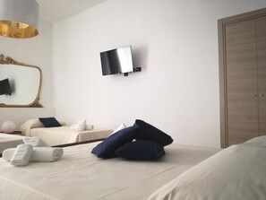 A hotel room with a bed, a television mounted on the wall, a mirror, and a wardrobe. - Spira Mirabilis Napoli (Naples)