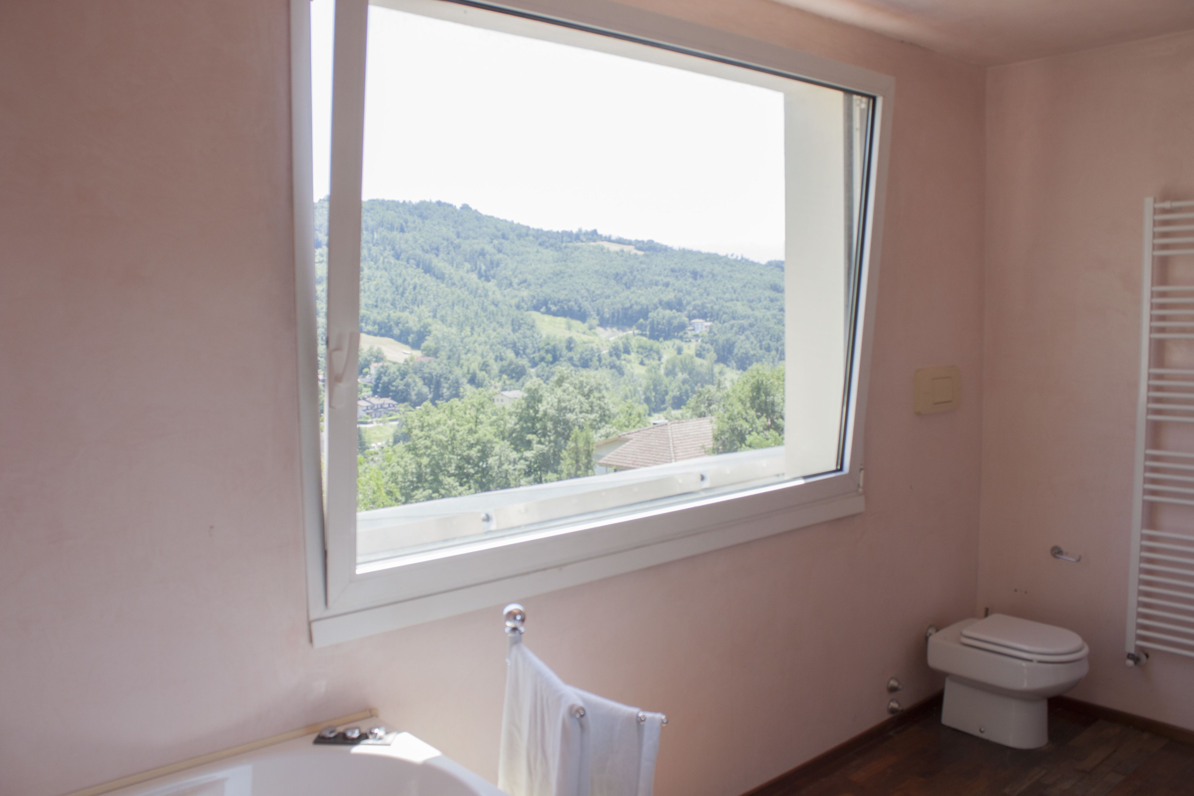 Un baño con ventana que da a una zona boscosa.
