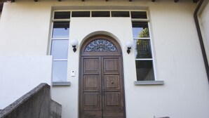 A building with a large wooden door, a small window, and a set of stairs leading up to the door. - Casa Bella Il Castello (Vergato)