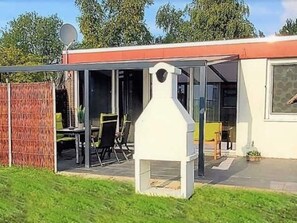 A covered outdoor area with a grill, a dining table, and chairs. - The cottage in Taddigshörn - nordseereise-net (Esens)