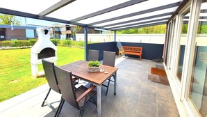 An outdoor patio with a table and chairs, a barbecue grill, and a bench. - The cottage in Taddigshörn - nordseereise-net (Esens)