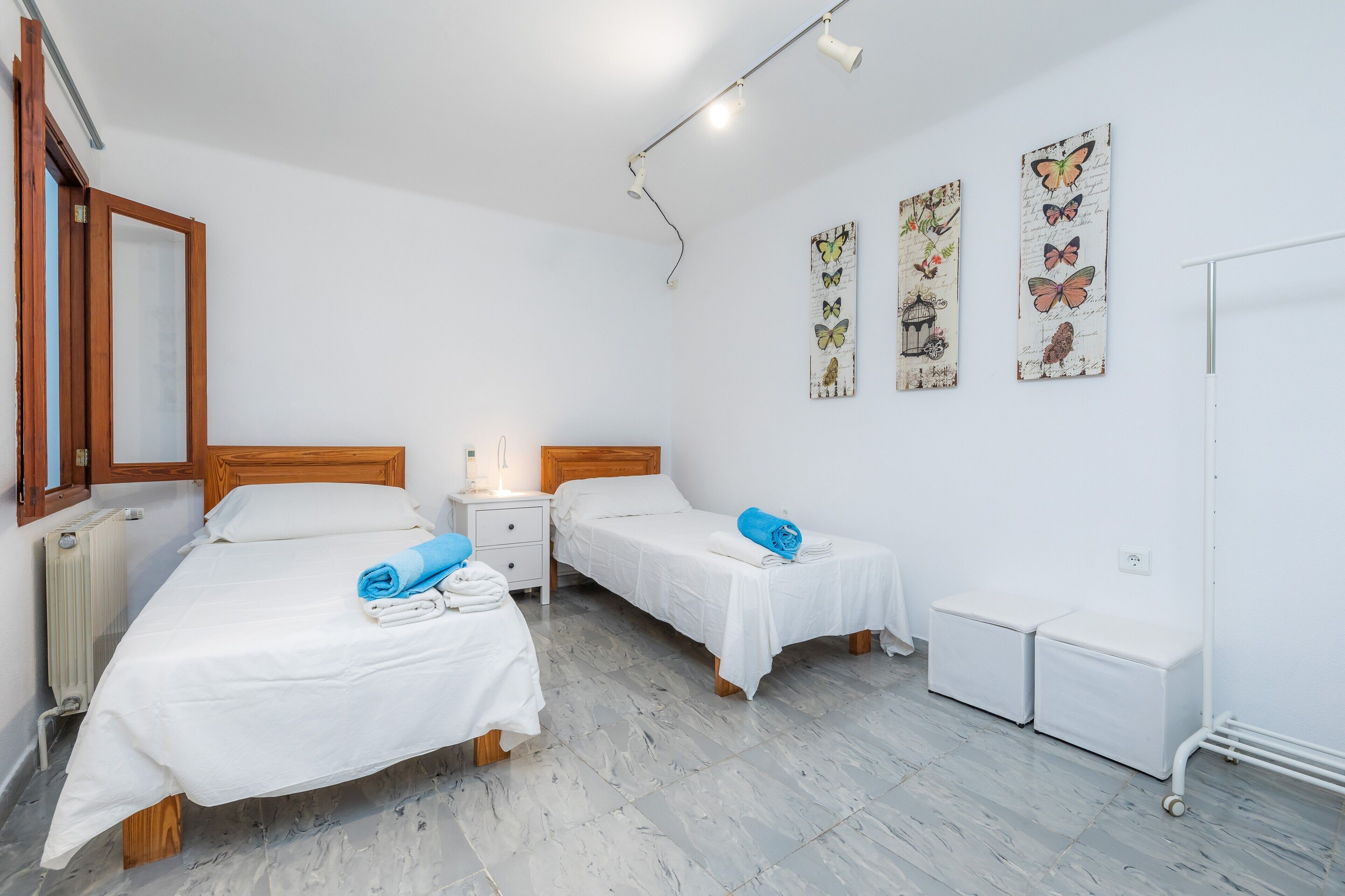 Une chambre d’hôtel avec deux lits, une table de chevet, un radiateur et des décorations murales représentant des papillons.