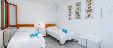 Une chambre d’hôtel avec deux lits, une table de chevet, un radiateur et des décorations murales représentant des papillons.