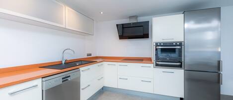 A modern kitchen with white cabinets, stainless steel appliances, and a wooden countertop.