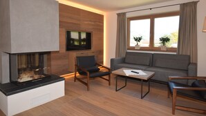 A modern living room with a fireplace, a sofa, a coffee table, and a TV mounted on the wall.