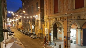 Eine Straße mit parkenden Autos und Fahrrädern, Gebäude mit historischer Architektur und einem Fußweg.