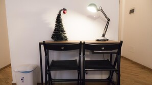 Ein Schreibtisch mit zwei Stühlen, ein kleiner Weihnachtsbaum, eine Schreibtischlampe und einem Papierkorb.