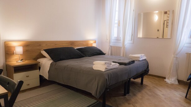 Ein ordentlich eingerichtetes Schlafzimmer mit Bett, Nachttisch, Lampe und Spiegel.