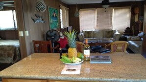 A kitchen with a granite countertop, wooden cabinets, and a dining area with a sofa and chairs. - Makaha on the Beach-Back in Time =Direct Oceanfront & Cove (Waianae)