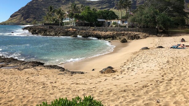 A beach with clear blue water, a sandy shore, and a mountain in the background. - Makaha on the Beach-Back in Time =Direct Oceanfront & Cove (Waianae)