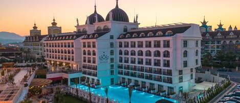 A large hotel with multiple domed structures, a swimming pool, and a parking area.