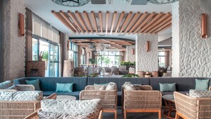 A spacious lounge area with a large sofa, wicker chairs, and a stone accent wall. - Side Royal Style Hotel (Manavgat)