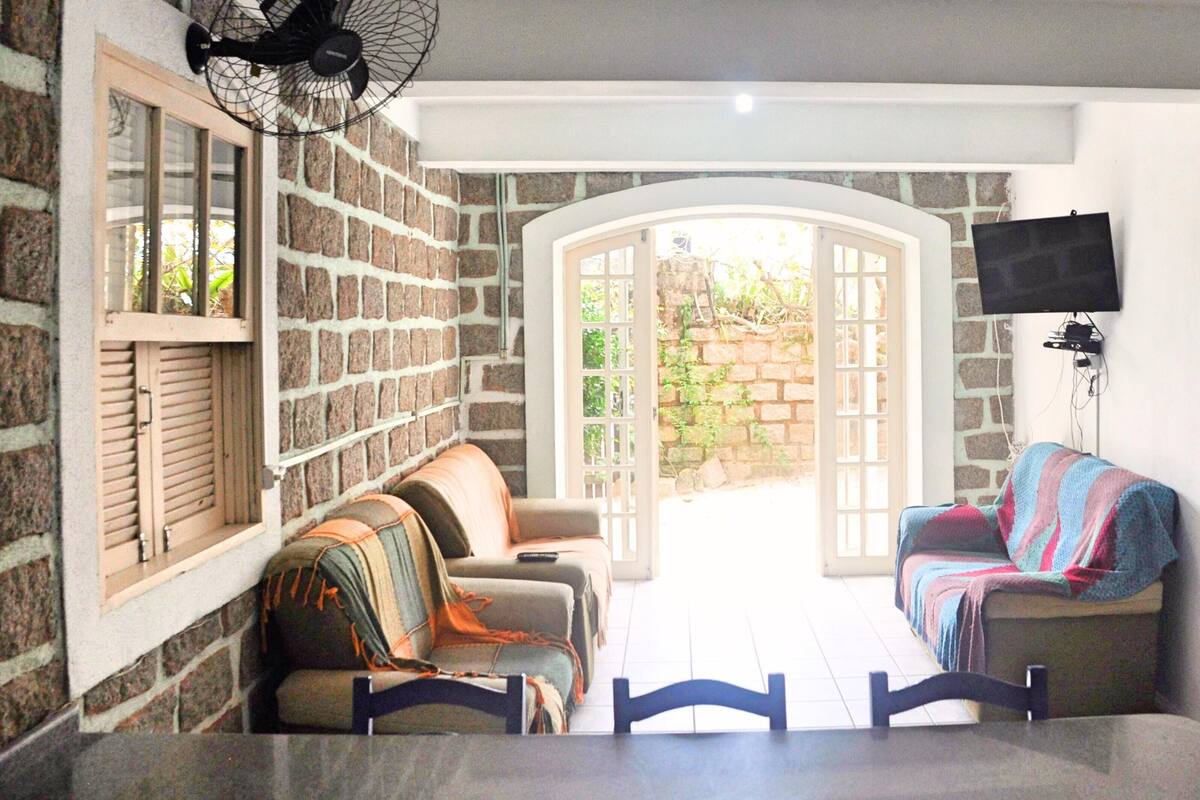 A cozy living area with a stone wall, a sofa, a chair, and a television mounted on the wall.