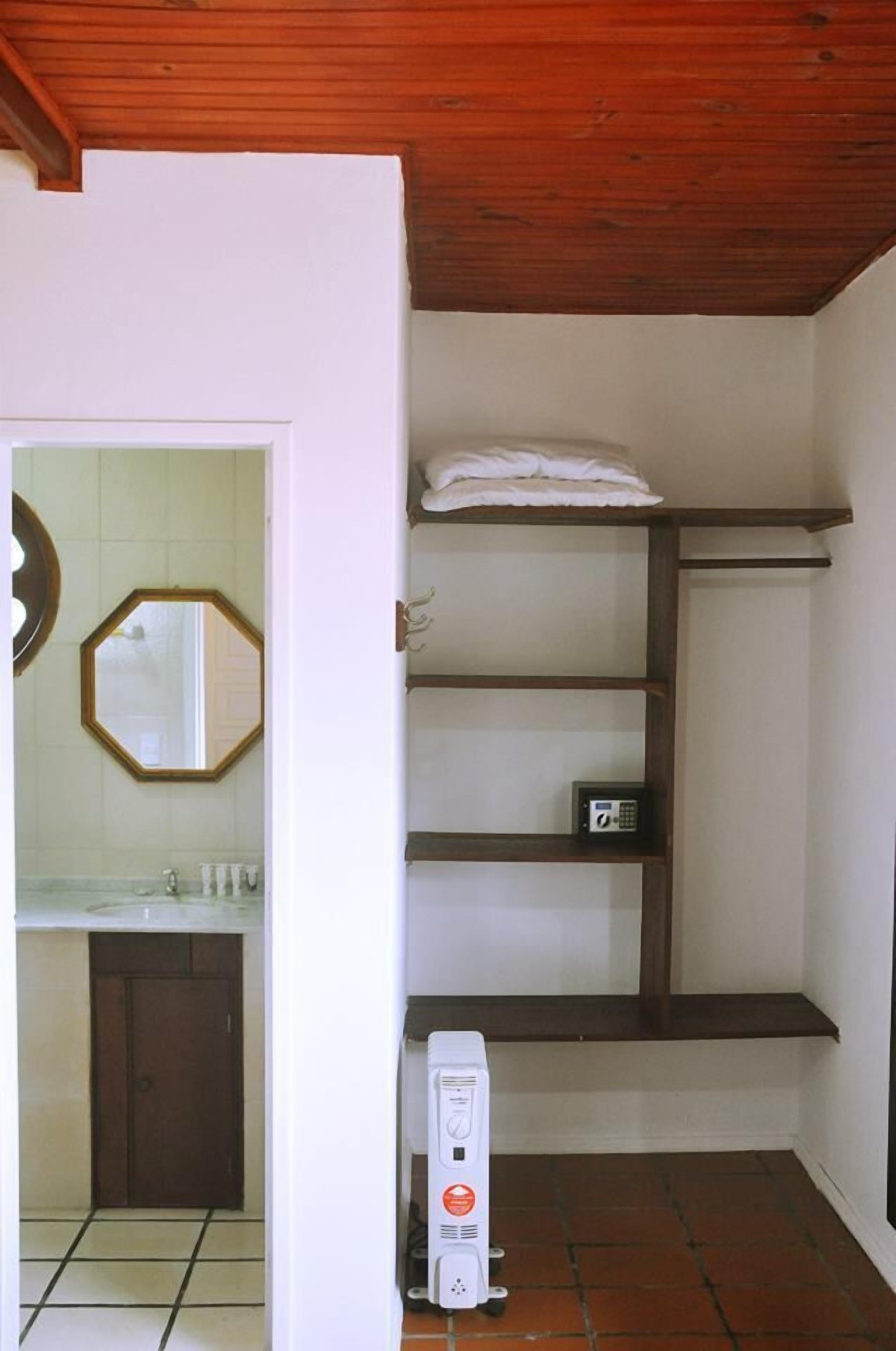 A bathroom with a tiled floor, a white sink, a mirror, and a shelf with a towel.