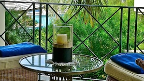 Ein Balkon mit Glastisch, Kerze und blauen Kissen.