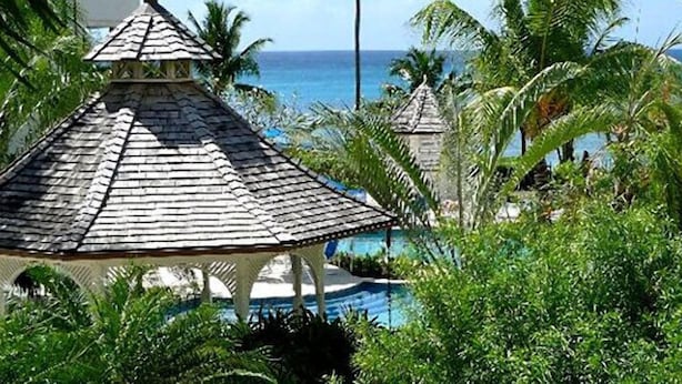 Ein Pavillon mit Ziegeldach mit Blick auf einen Pool und den Ozean.
