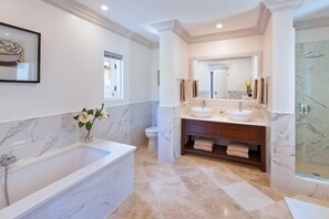 A modern bathroom with a large bathtub, double sinks, and a walk-in shower. - Villa Moon Dance (Paynes Bay)