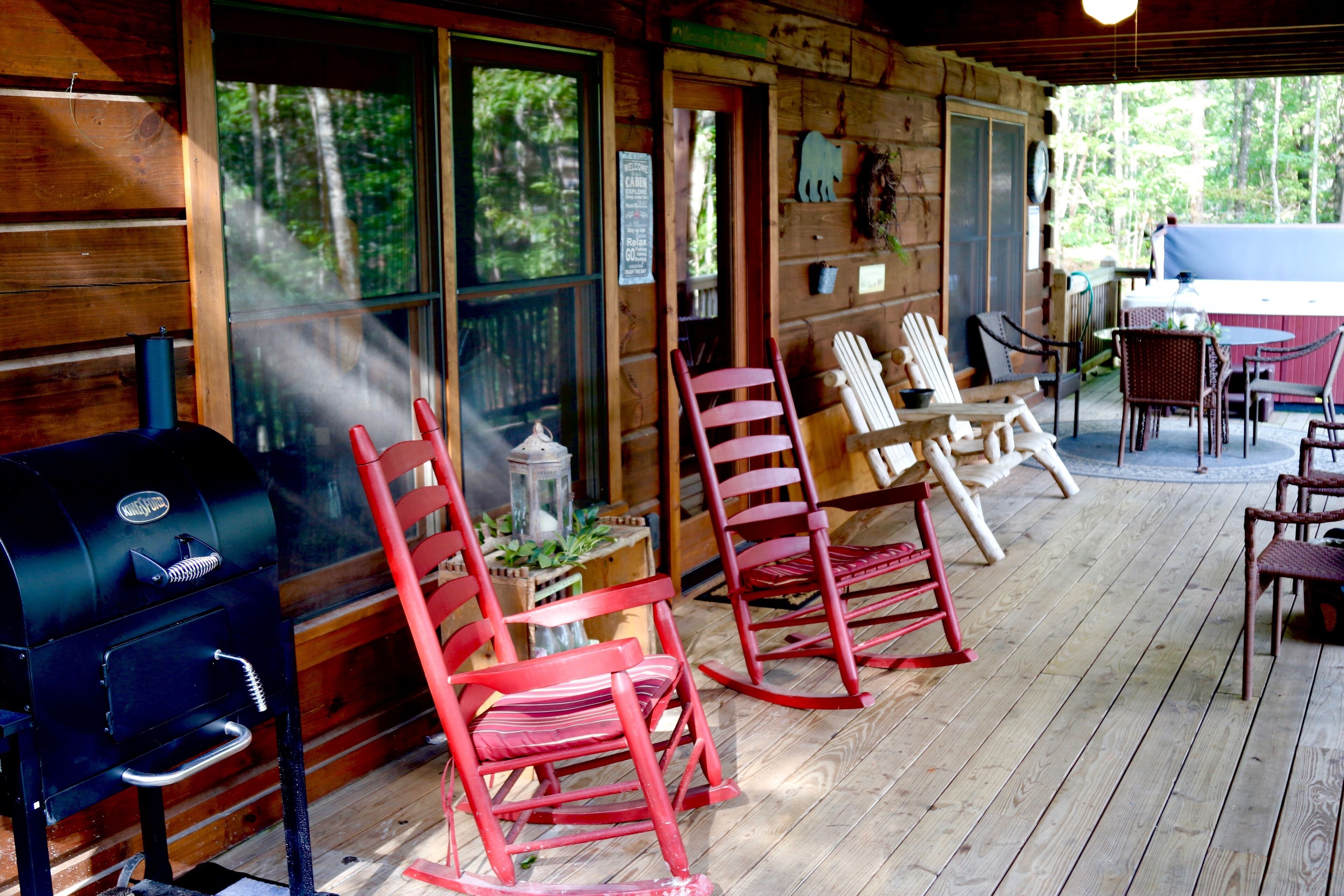 A wooden deck with rocking chairs, a grill, and a covered table area.