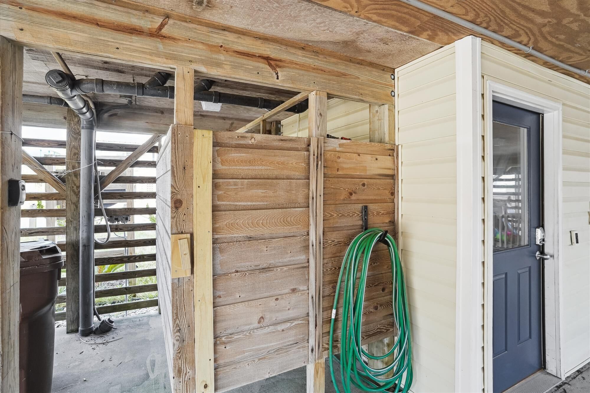 A partially constructed wooden structure with exposed beams and a green garden hose.