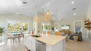 A modern kitchen with a central island, white cabinetry, and pendant lighting. - 4 Beds 4.5 Bath with Pool 3 Blocks to Beach (Anna Maria)