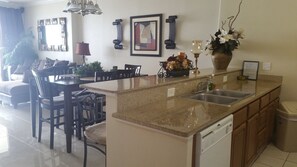 A modern kitchen with a central island, a dining area with chairs, and a living room with a sofa. - 2 Bedroom/2 Bath Beachfront!  (Panama City Beach)