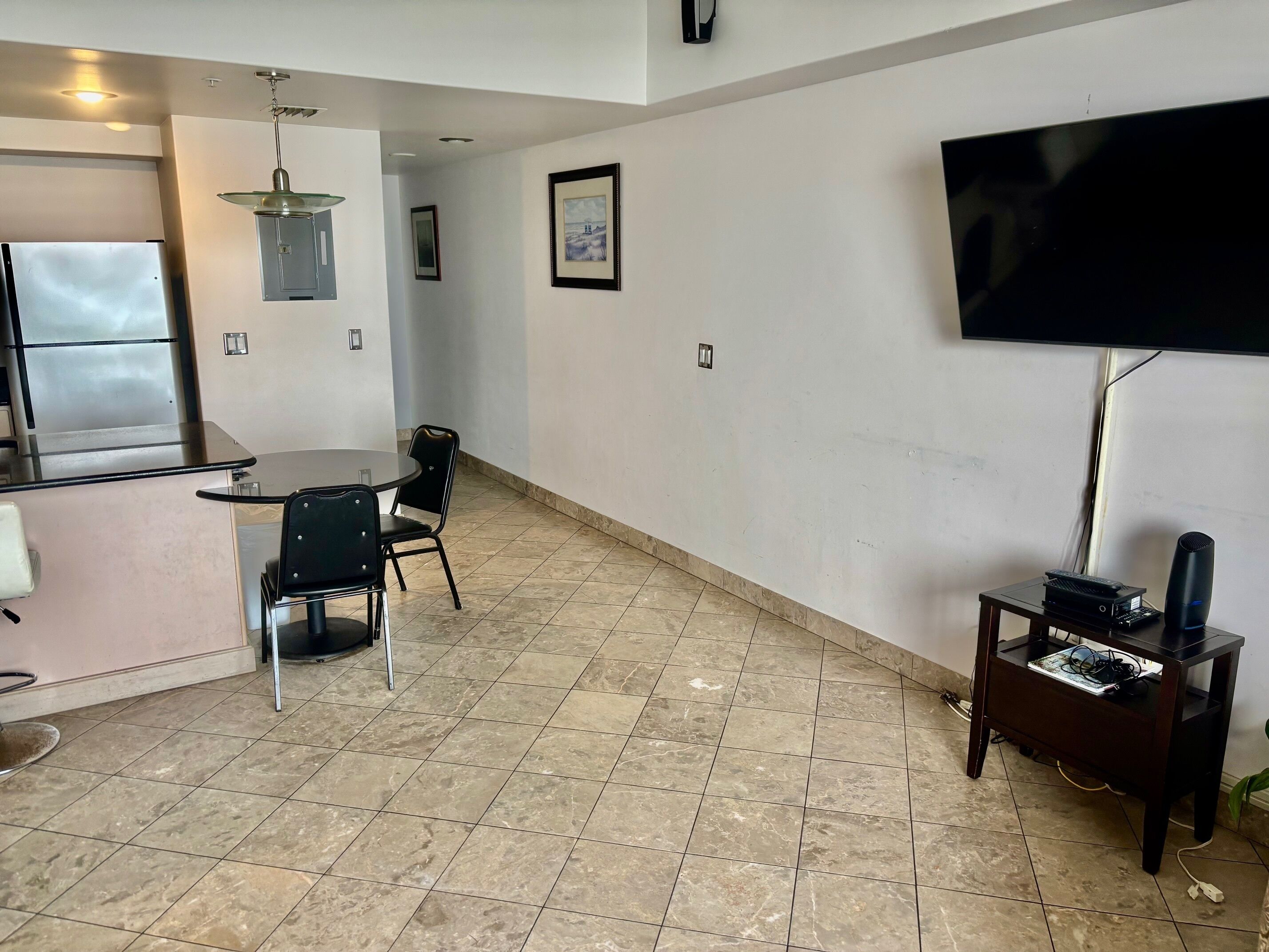 Un espacio habitable compacto con zona de cocina, mesa de comedor y televisor de pantalla plana montado en la pared.