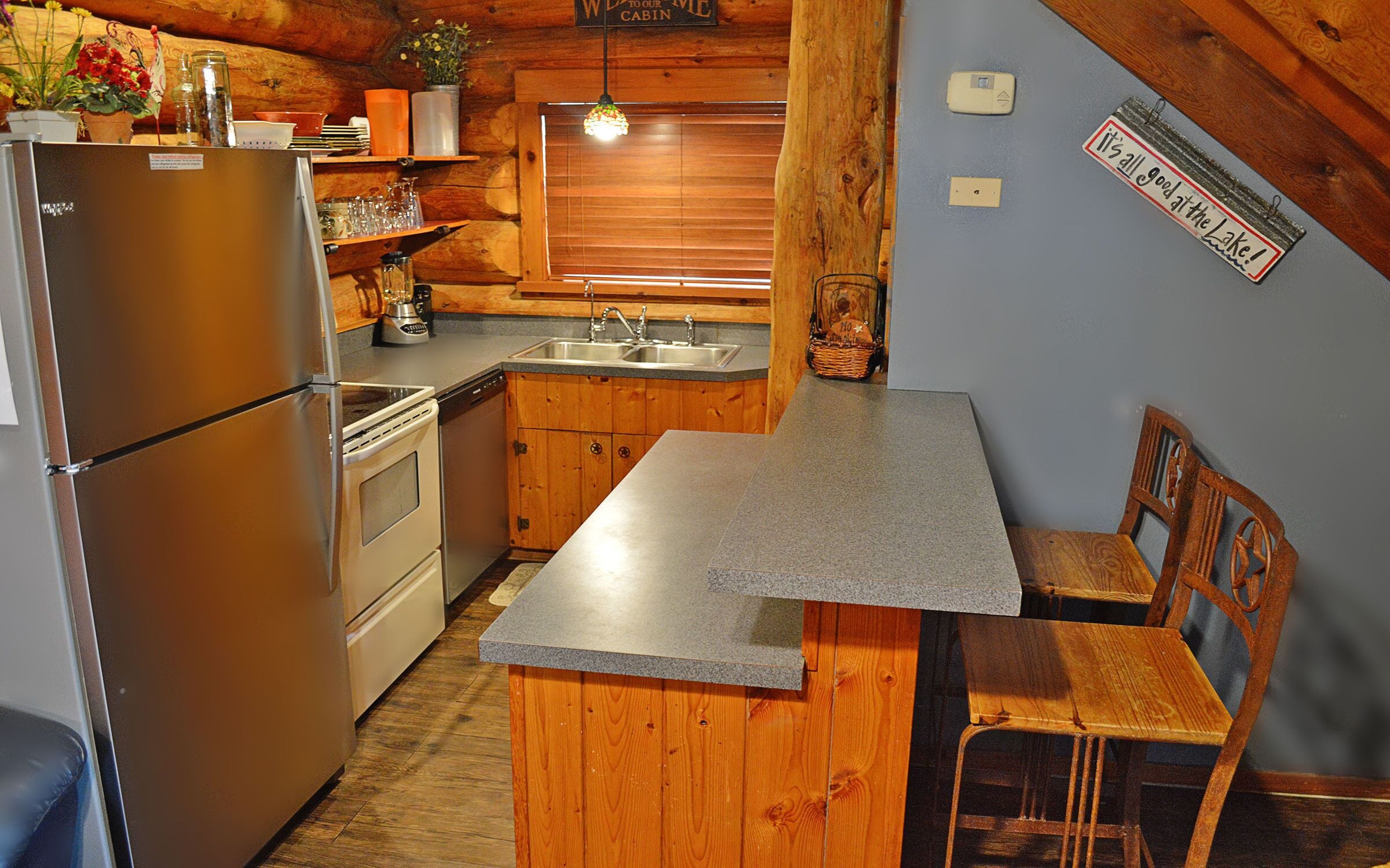 Une cuisine compacte avec des meubles en bois, un four encastré, un réfrigérateur et un plan de travail en granit.