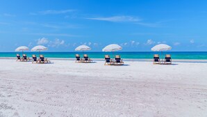 A beach with white sand and clear blue water. There are several beach chairs and umbrellas arranged in rows. - 4 Bed 4.5 Bath Family Friendly, 3 Blocks to Gulf (Anna Maria)