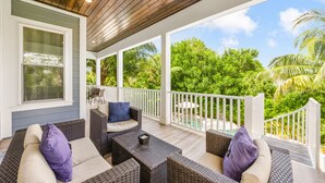 A covered outdoor seating area with wicker furniture and a view of lush greenery. - 4 Bed 4.5 Bath Family Friendly, 3 Blocks to Gulf (Anna Maria)