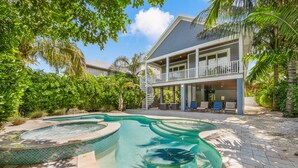 A two-story house with a swimming pool, surrounded by lush greenery and palm trees. - 4 Bed 4.5 Bath Family Friendly, 3 Blocks to Gulf (Anna Maria)