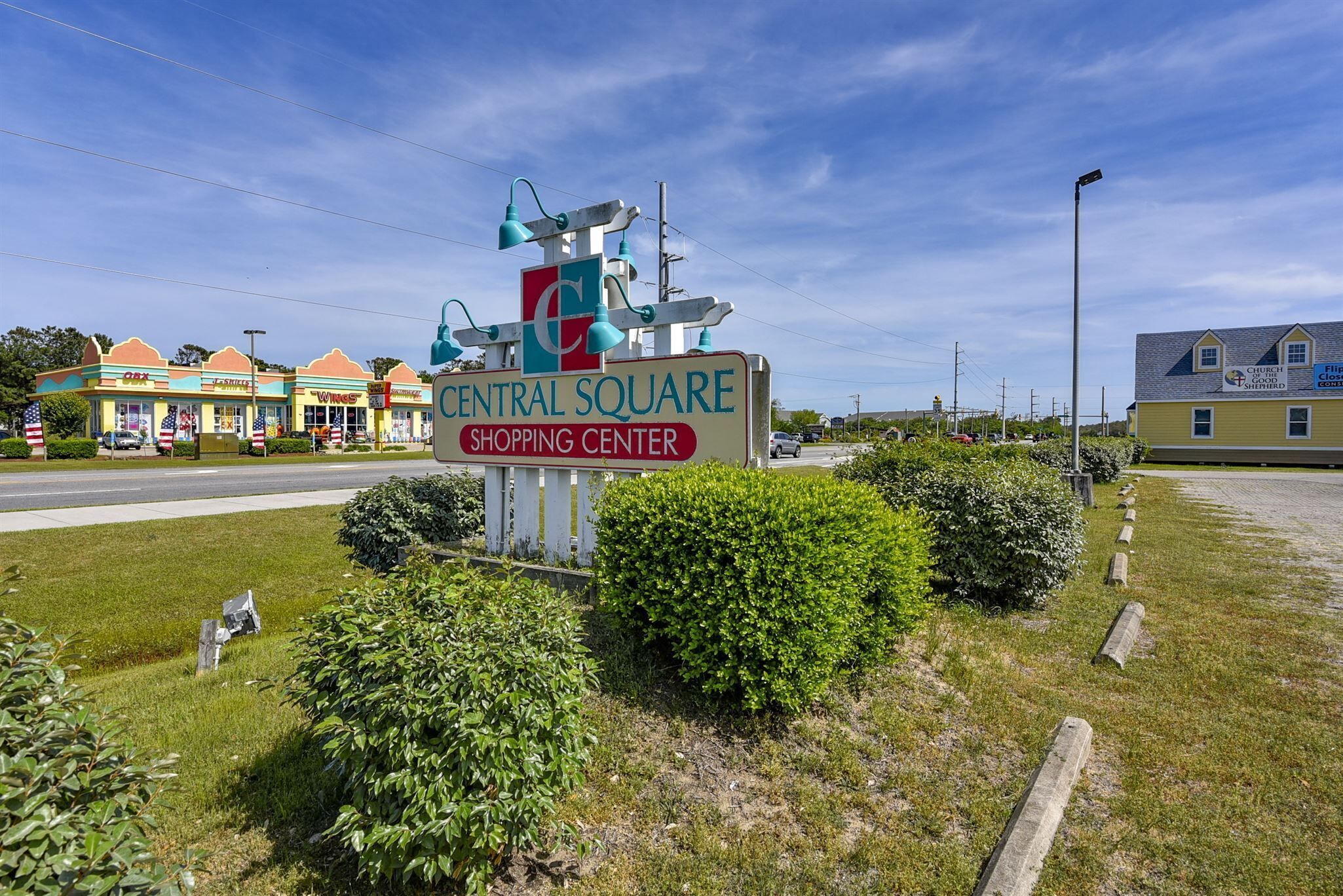A Central Square Shopping Center sign with a unique structure and a parking lot in the foreground.