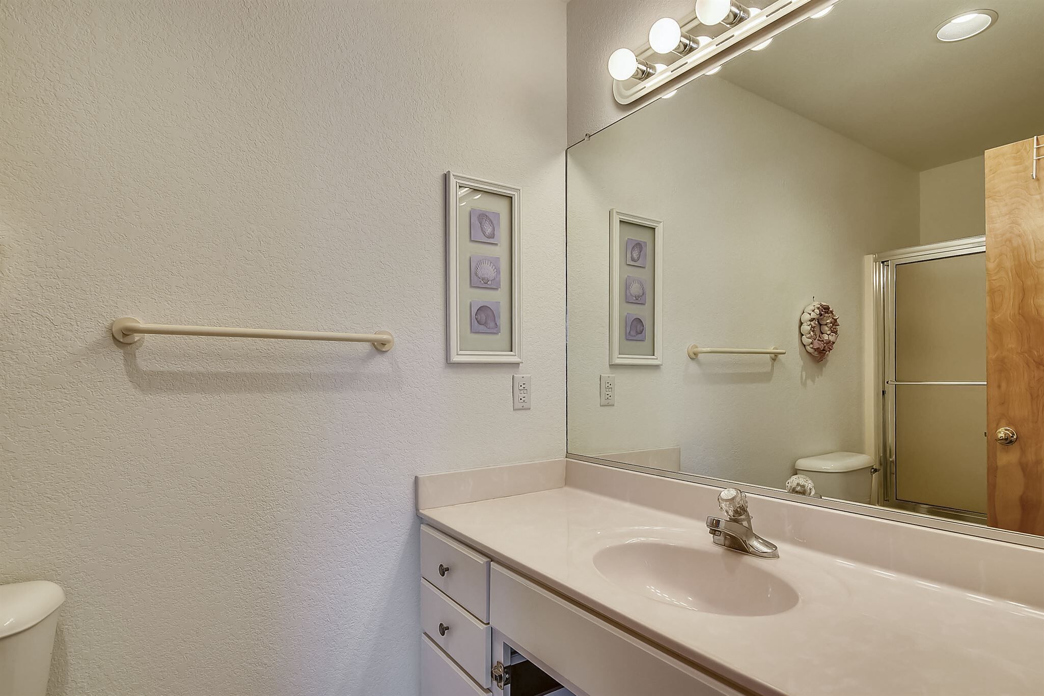 A bathroom with a white sink, a mirror, and a towel rack.