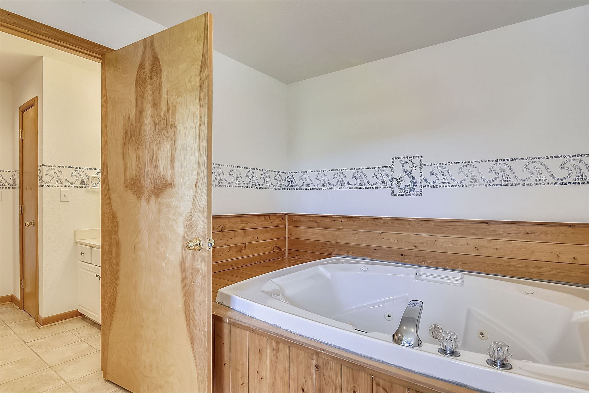A bathroom with a wooden vanity, a bathtub, and a patterned wall.