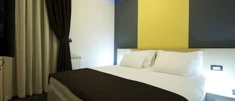 Habitación de hotel con cama, cortinas y pared con una combinación de colores amarillo y gris.