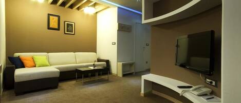 Una sala moderna con un sofá, una mesa de centro, un televisor de pantalla plana y un teléfono sobre un mueble consola.