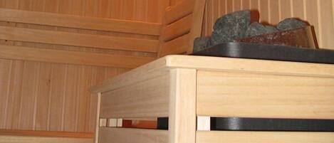 A sauna room with wooden benches and a wall-mounted heater.
