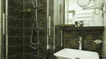 A shower with a glass door, a white sink, and a towel rack.