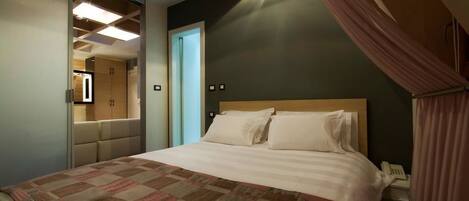 Una habitación de hotel con cama, armario, espejo y teléfono.