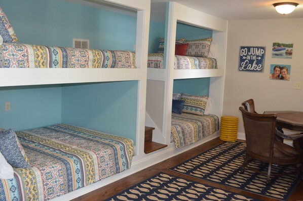 A room with bunk beds, a dining table, and a rug with a fish pattern.