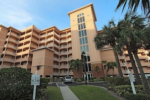 A multi-story hotel with balconies, a parking area, and palm trees. - Penthouse w/Designer Décor! 806 Harborview Grande (Clearwater)