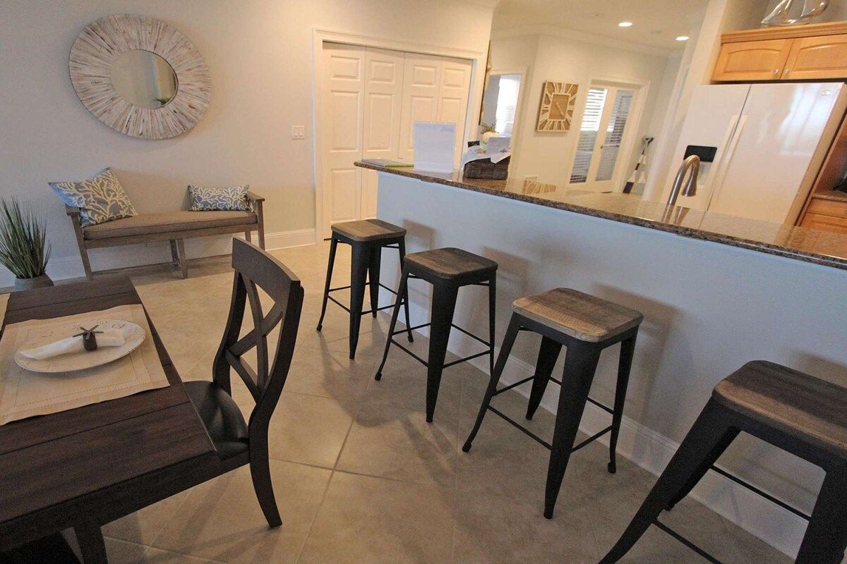 A modern kitchen with a bar area, a dining table with chairs, and a bench.